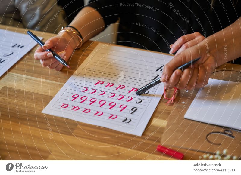 Gesichtslose Frau lernt Schriftzug bei Tisch Beschriftung zeichnen Papier Handschrift Beruf Schreibtisch Arbeitsplatz Kunst kreativ Handwerk graphisch Bildung