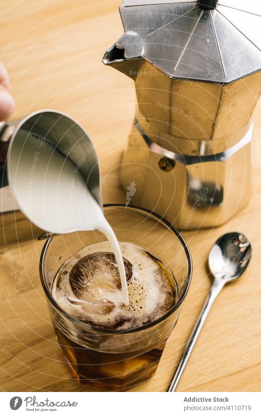 Unbekannter Barista füllt ein Glas Kaffee mit Milch auf eingießen melken Eis hinzufügen brauen trinken Getränk vorbereiten Dienst kalt Tasse Koffein liquide