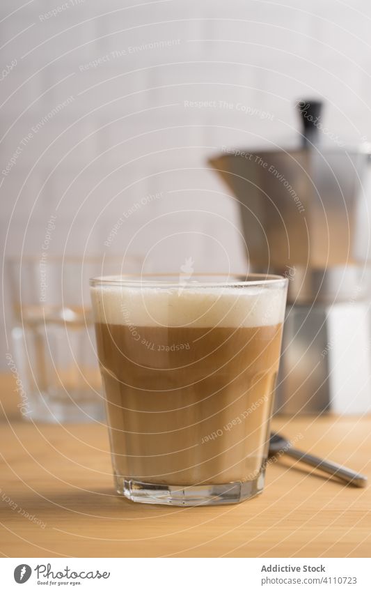Frischer Kaffee mit Milch im Glas Bierschaum Getränk trinken Koffein Latte Cappuccino Tasse schäumen braun Frühstück melken hölzern heiß brauen Dienst Tisch