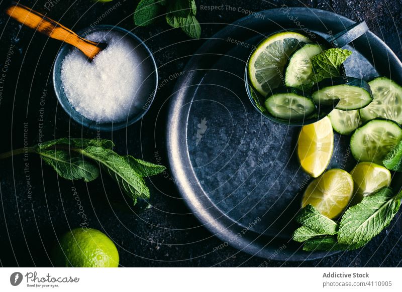 Zutaten für Gurken-Detox-Getränk auf dem Tisch Salatgurke Entzug trinken Bestandteil Kalk Minze Zucker Zitrone Tasse Tablett dunkel frisch Gesundheit natürlich