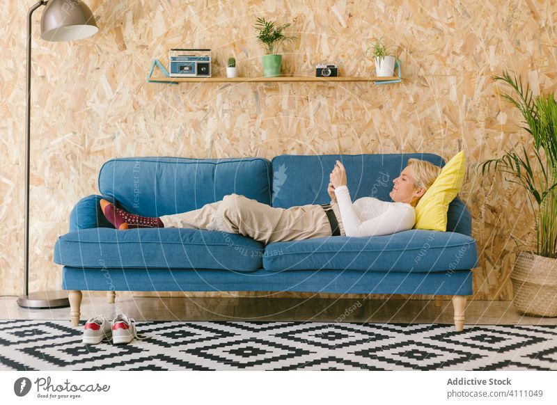 Frau ruht sich während des Arbeitstages auf der Couch aus Geschäftsfrau Pause Smartphone Liege ruhen benutzend sich[Akk] entspannen Lügen Design Büro Komfort