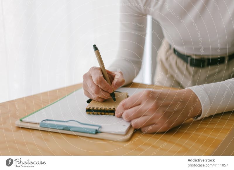 Crop-Frau macht sich Notizen am Holzschreibtisch Notizblock Business zur Kenntnis nehmen schreiben Schreibtisch Arbeitsplatz Beruf Tisch kreativ Textfreiraum