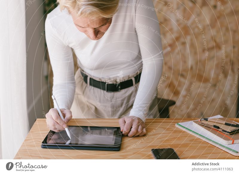 Konzentrierte Frau, die ein Tablet mit einem Stift benutzt und im Büro arbeitet Geschäftsfrau Tablette benutzend Schreibtisch Designer Arbeitsplatz Griffel