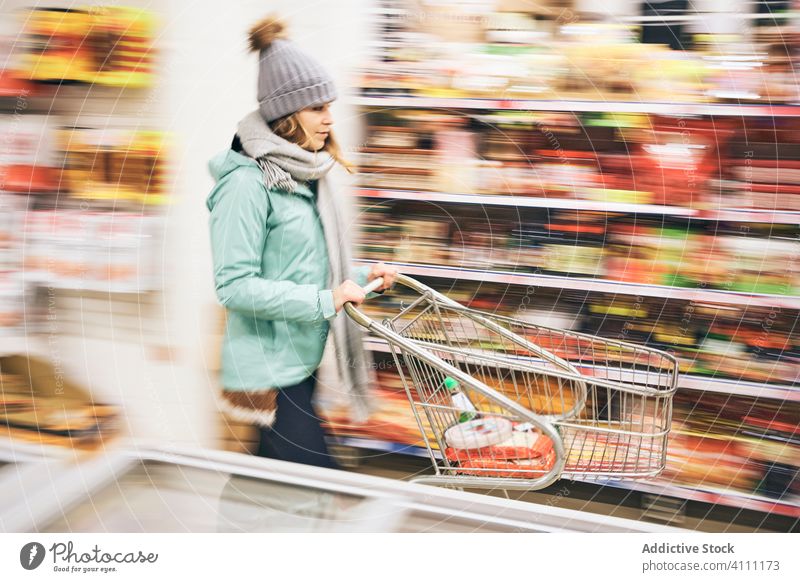 Frau beim Einkaufen im Supermarkt Laden Karre Lebensmittel Käufer Kunde Kauf Lebensmittelgeschäft defokussiert Werkstatt Bewegung Einzelhandel Produkt Handwagen