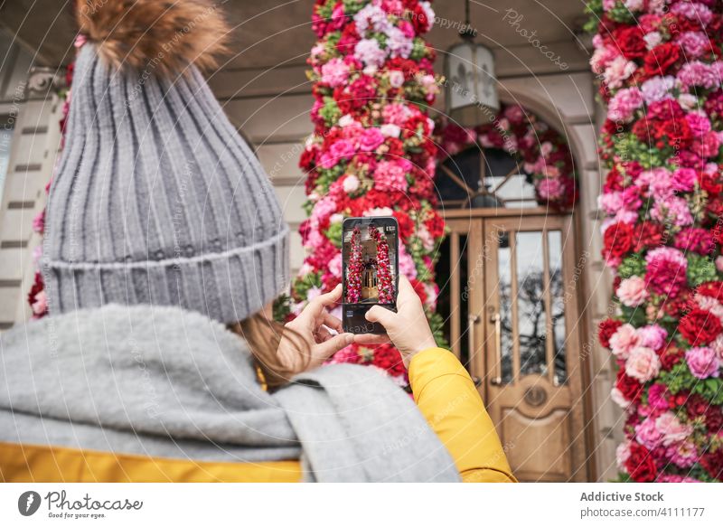 Anonyme Frau, die ein Haus mit Blumenschmuck fotografiert Smartphone fotografieren Dekoration & Verzierung Außenseite Straße Stadt schießen Gedächtnis Moment