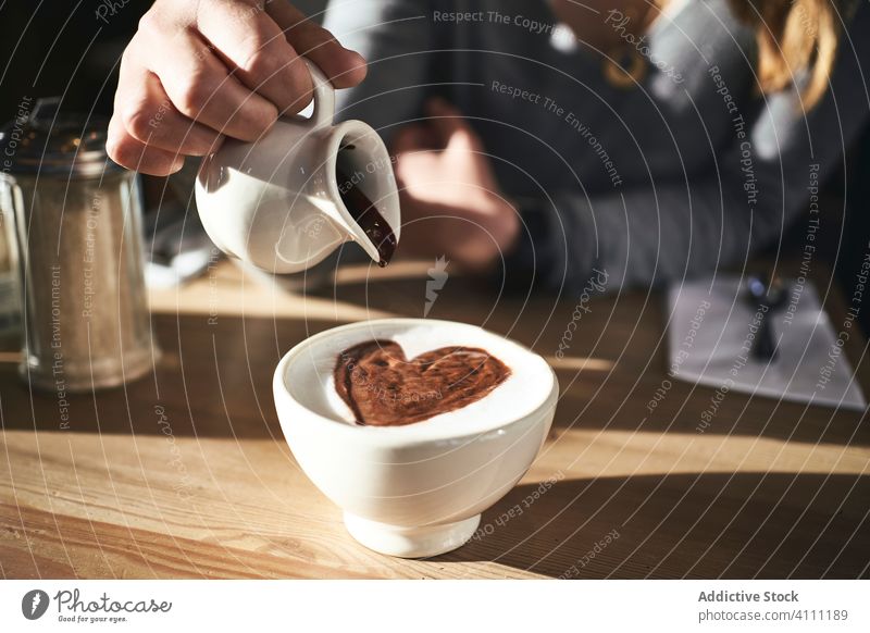 Anonyme Frau gibt Schokoladensirup in ein Heißgetränk Tasse Getränk Café warm kalt Tisch eingießen süß Kakao Lebensmittel hinzufügen trinken warme Kleidung