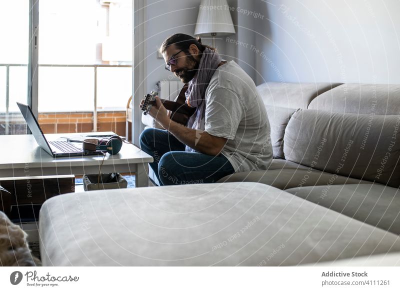 Stilvoller Gitarrist auf der Couch im Wohnzimmer Mann spielen Gitarre sitzen Liege Sofa männlich lässig Musik Songwriter Komponist Dichter heimwärts Lifestyle