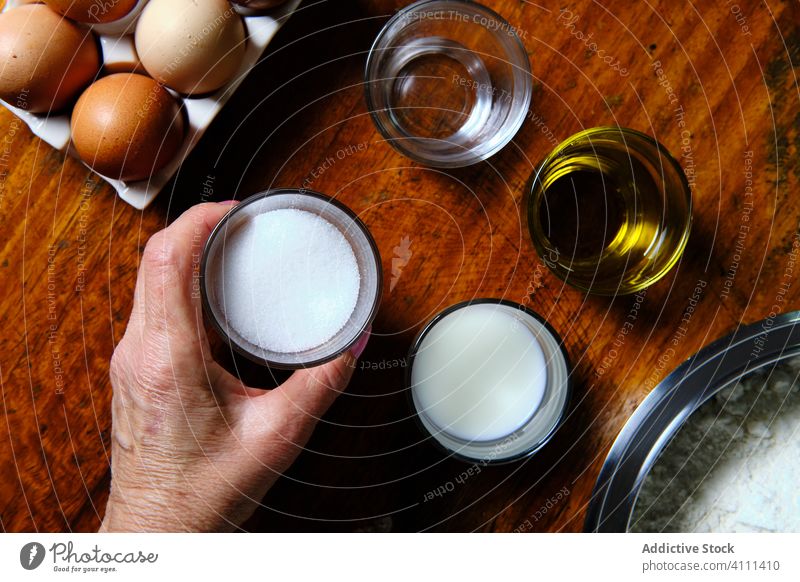 Eine Frau nimmt eine Zutat für ein Gebäckstück vom Tisch Bestandteil Koch Küche heimwärts Tasse Krapfen Lebensmittel Zucker Erdöl Wasser melken Molkerei Mehl