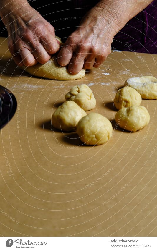 Crop-Frau rollt Kugeln aus Teig Teigwaren Ball rollen Tisch Gebäck Koch heimwärts Küche weich Doughnut Krapfen vorbereiten Lebensmittel Bestandteil Rezept