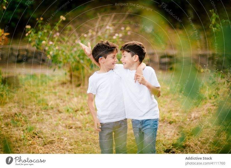 Glückliche Zwillingsjungen, die sich im Park umarmen und gegenseitig anschauen Bruder Zusammensein Umarmen Junge Kind Lächeln Liebe Kindheit Natur gleich Sommer