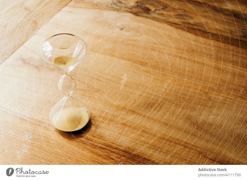 Sanduhr mit Sand auf Holztisch Zeit Tisch fließen Glas elegant zerbrechlich Design hölzern Form Nutzholz Zeitschaltuhr Minute verschütten warten vergangen