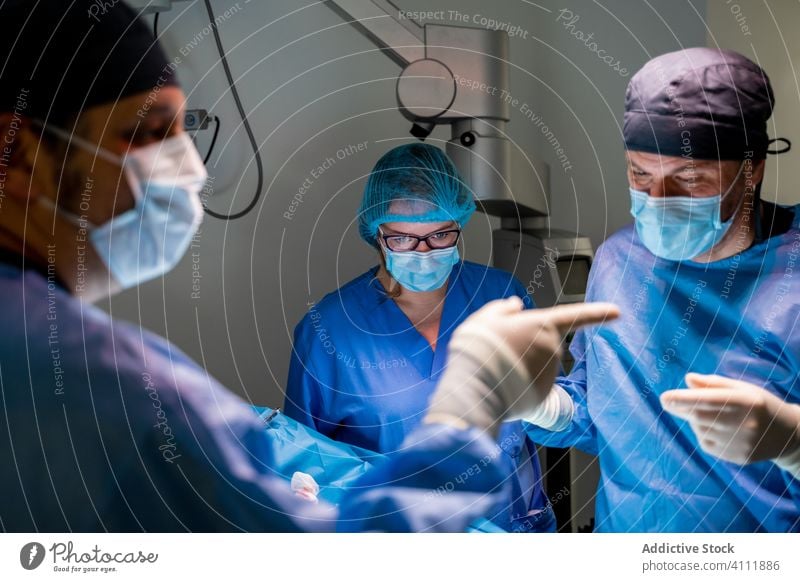 Medizinisches Personal bei einer Operation in einer modernen Klinik Chirurg diskutieren Chirurgie Krankenhaus Mundschutz Sanitäter konsultieren Krankenpfleger