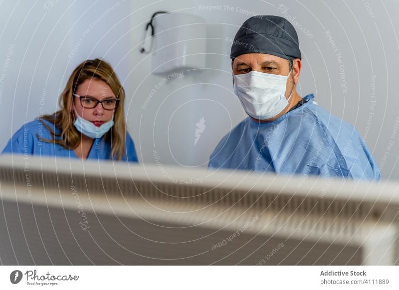 Arzt und Assistentin überprüfen Informationen auf dem Bildschirm, während sie eine diagnostische Patientenerkrankung in einer modernen Klinik durchführen