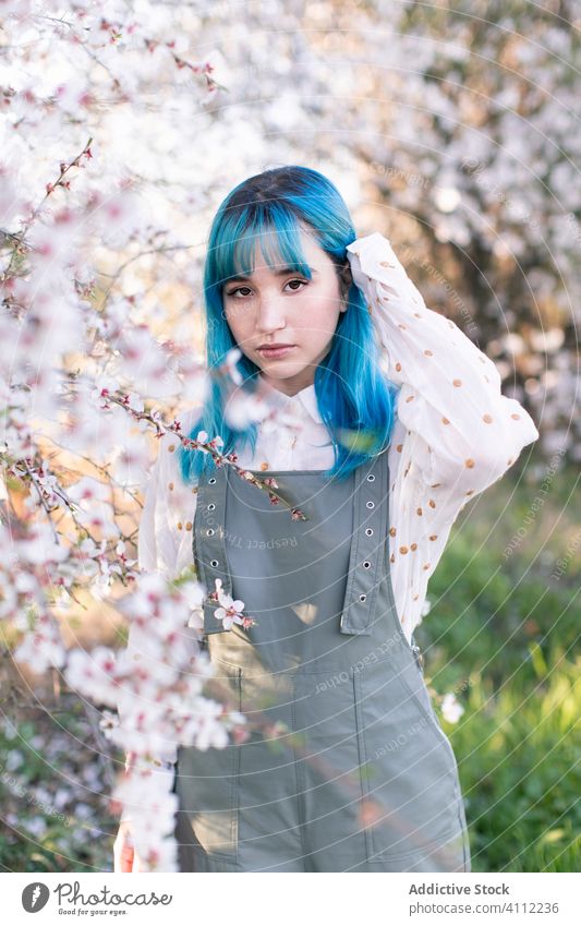 Trendige Frau im blühenden Garten Frühling Blütezeit Teenager alternativ gefärbtes Haar Blume Stil trendy modern jung blaue Haare Baum Natur geblümt schön
