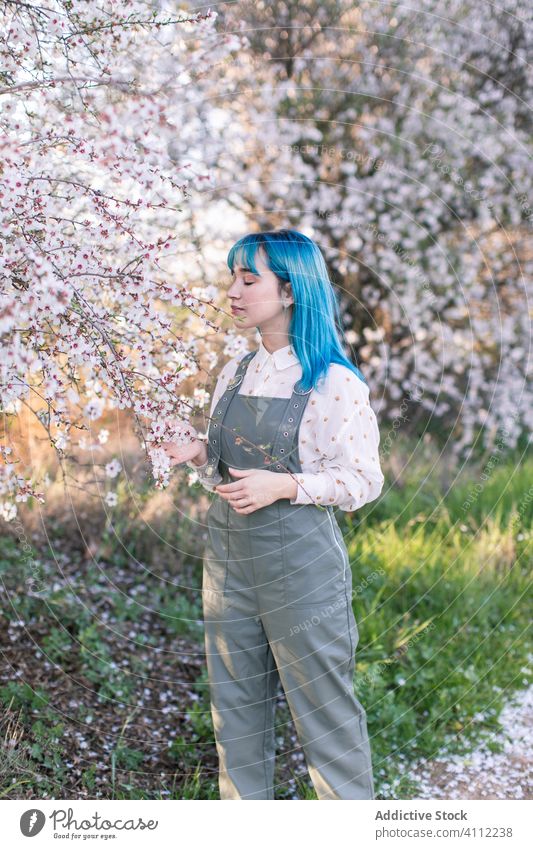 Trendige Frau im blühenden Garten Frühling Blütezeit Teenager riechen Duft alternativ gefärbtes Haar Blume Stil trendy modern jung blaue Haare Baum Natur