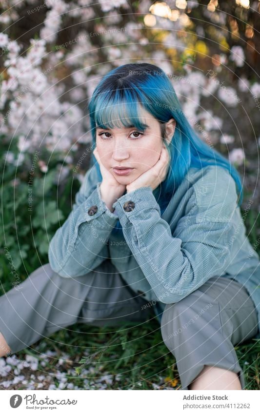 Nachdenkliche junge Frau sitzt im blühenden Garten trendy traurig Teenager Melancholie gefärbtes Haar alternativ Blütezeit Einsamkeit nachdenklich sitzen Stil