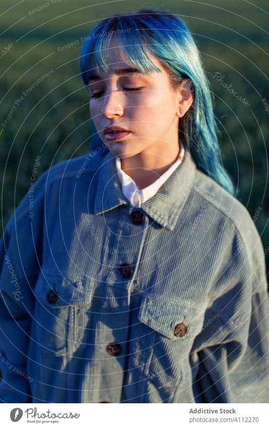 Traurige stilvolle Frau im Feld stehend trendy Melancholie besinnlich traurig informell gefärbtes Haar allein Hipster blaue Haare Stil Mode Windstille