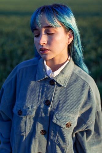 Traurige stilvolle Frau im Feld stehend trendy Melancholie besinnlich traurig informell gefärbtes Haar allein Hipster blaue Haare Stil Mode Windstille