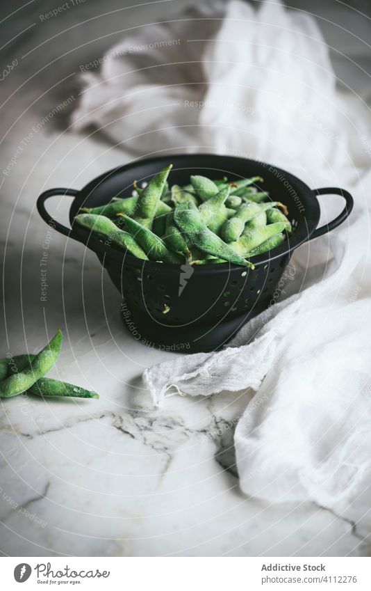 Sieb mit ungekochten Edamame auf dem Tisch Sojabohne roh unreif Serviette Gaze frisch Lebensmittel asiatisch organisch natürlich Bestandteil Vegetarier Gemüse