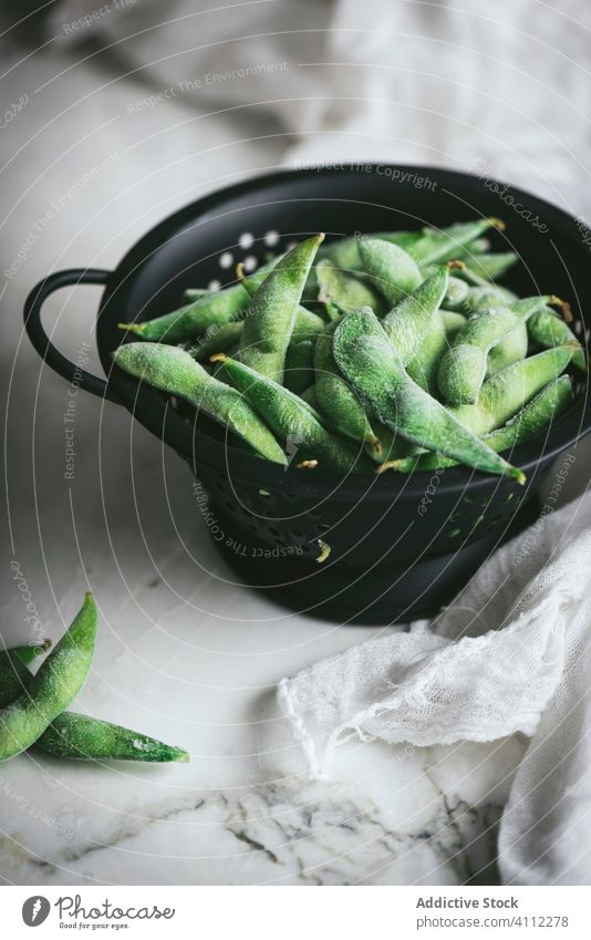 Sieb mit ungekochten Edamame auf dem Tisch Sojabohne roh unreif Serviette Gaze frisch Lebensmittel asiatisch organisch natürlich Bestandteil Vegetarier Gemüse