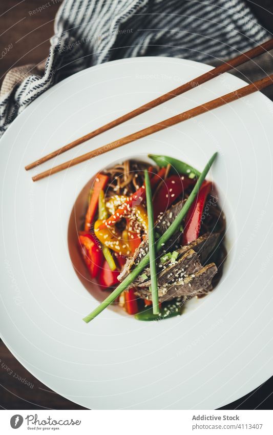 Leckere orientalische Nudeln in weißem Teller mit Stäbchen Lebensmittel Speise asiatisch Essstäbchen Fleisch Gemüse Tradition Mahlzeit lecker hölzern Abendessen