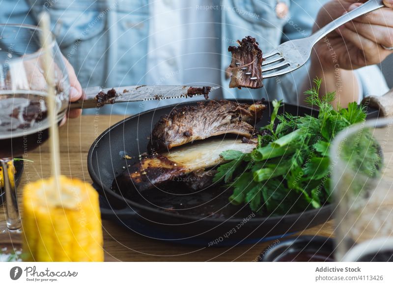 Person isst gegrilltes Fleisch in einem Restaurant Grillrost Mais Steak essen Kraut grün Braten geschmackvoll Knochen Barbecue rustikal hölzern Lebensmittel