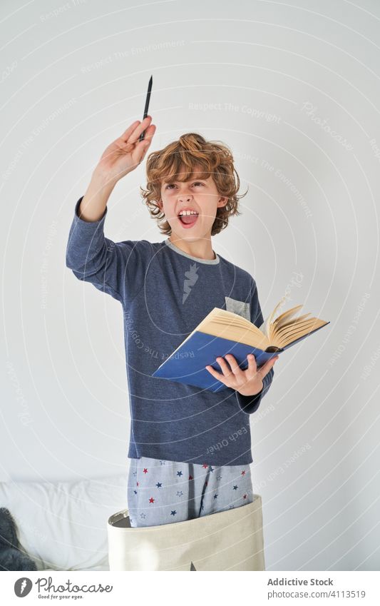 blondes Kind im Pyjama mit einem Buch, das Forschung betreibt Kinder Spiel behüten Fröhlichkeit Genuss spielen Raum im Innenbereich Freude Party Komfort