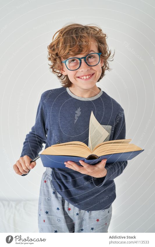 blondes Kind im Pyjama mit einem Buch, das Forschung betreibt Kinder Spiel behüten Fröhlichkeit Genuss spielen Raum im Innenbereich Freude Party Komfort
