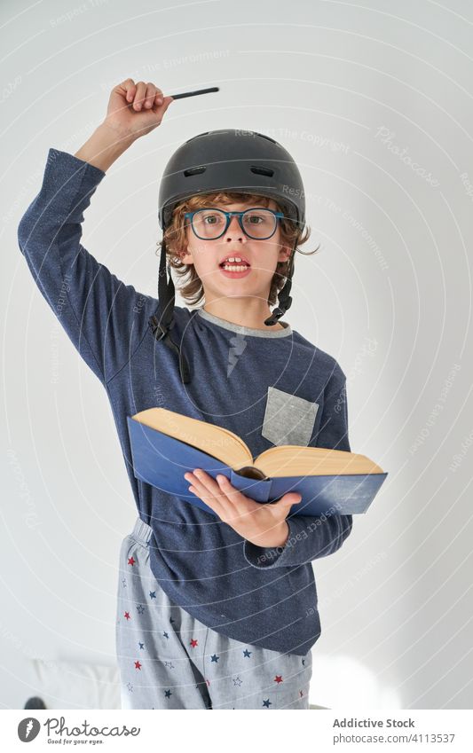 blondes Kind im Schlafanzug mit einem Helm, einer Taschenlampe und einem Buch, das Forschung spielt Komfort träumen wow Vorstellungskraft bequem Kinder freudig