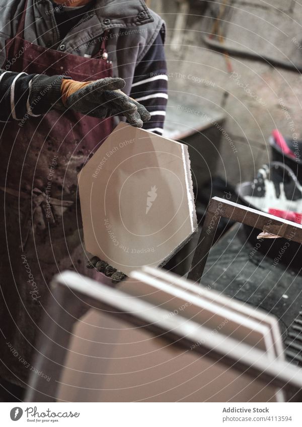 Anonymer Handwerker in Schürze mit Keramikfliesen in der Werkstatt Meister Produkt Kunsthandwerk Fliesen u. Kacheln Sechseck Fabrik professionell