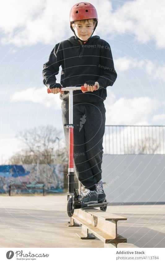 Junge fährt Roller auf einer Rampe im Park Skateplatz Tretroller extrem Sport urban aktiv üben Mitfahrgelegenheit Kick Teenager Trick Skateboard männlich Stunt