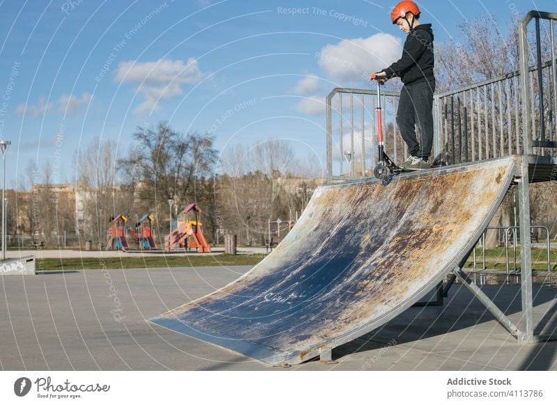 Junge fährt Roller auf einer Rampe im Park Skateplatz Tretroller extrem Sport urban aktiv üben Mitfahrgelegenheit Kick Teenager Trick Skateboard männlich Stunt