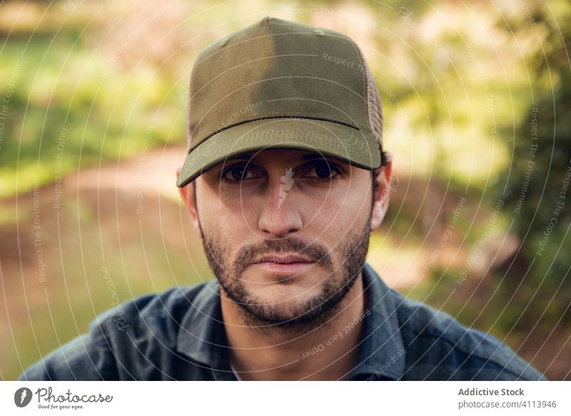 Mann in kariertem Hemd und Baseballmütze im Wald gutaussehend männlich Porträt lässig attraktiv Hut Erwachsener Person Stil nachdenklich Kaukasier selbstbewusst