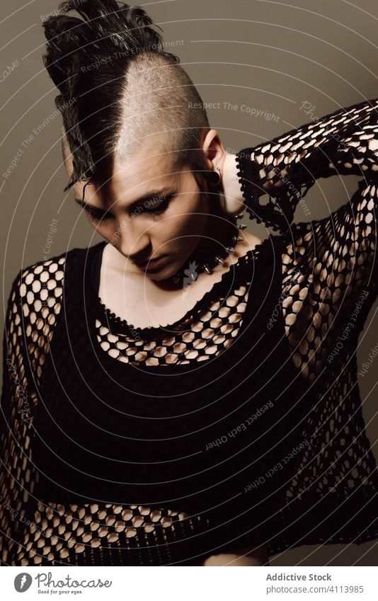Ernste erwachsene Dame mit Irokesenschnitt vor braunem Hintergrund Frau Punk Stil selbstbewusst Subkultur modern auflehnen mohawk Vorschein dunkel Model