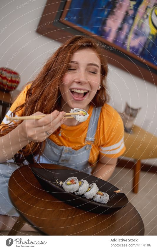 Junge Frau isst Sushi zu Hause essen heimwärts Essstäbchen Japanisch jung Tisch lässig Lebensmittel Ingwer Meeresfrüchte Fisch Reis Teller rollen asiatisch