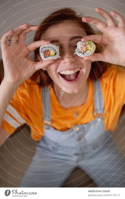 Junge Frau spielt mit Sushi Spaß Glück Auge heimwärts Mittagessen Japanisch jung geschmackvoll Reis Meeresfrüchte Lebensmittel rollen Lächeln aufgeregt