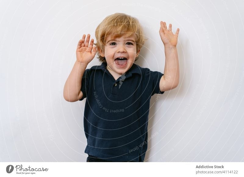 Fröhliches kleines Kind, das die Finger zeigt und die Hände hochhebt heiter Lachen wenig wow Spiel expressiv Glück Hand erhoben Junge Energie hochreichen