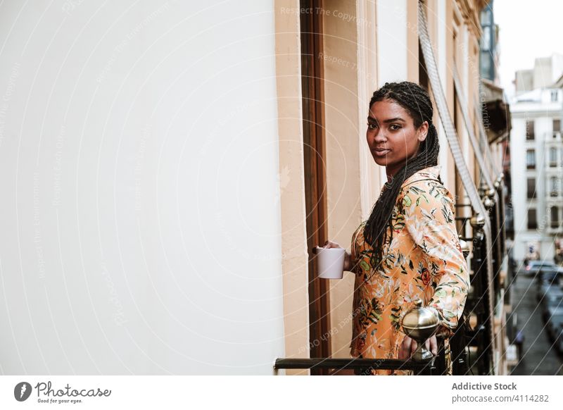 Junge Frau mit Tasse Kaffee auf dem Balkon stehend Windstille trinken lässig heimwärts ruhig nachdenklich sich[Akk] entspannen jung Afroamerikaner schwarz