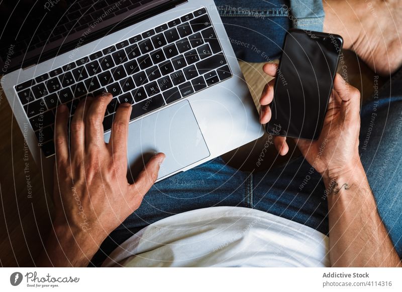 Freiberufler mit Laptop und Smartphone Mann benutzend freiberuflich heimwärts Stock sitzen Internet Anschluss männlich Browsen Gerät Apparatur online Surfen