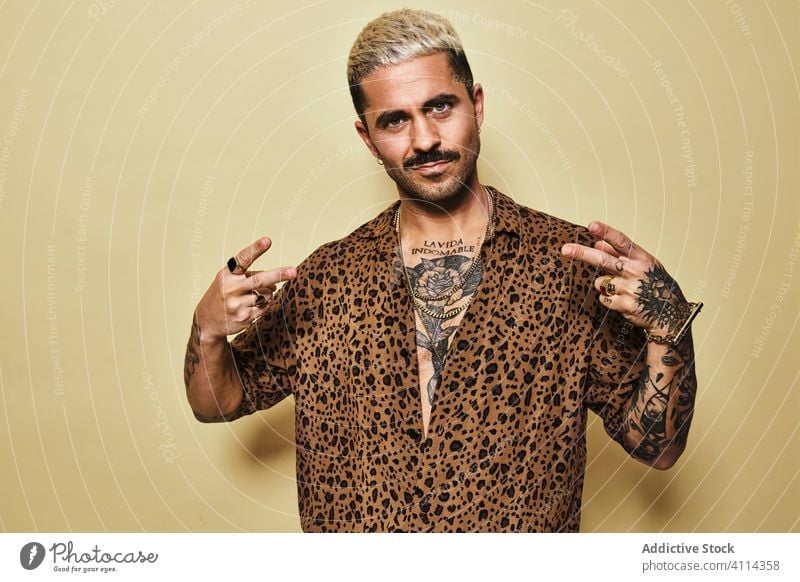 Stilvoller Macho-Mann mit Friedensgebärde trendy Tattoo genehmigen cool positiv selbstbewusst Mode jung ethnisch Zeichen zeigen gutaussehend männlich Vollbart