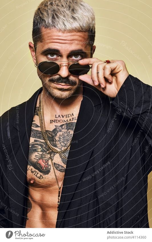 Provokativer Mann ohne Hemd in schwarzem Mantel und Sonnenbrille Macho cool trendy brutal Tattoo Stil Mode unrasiert Model Persönlichkeit muskulös Vollbart