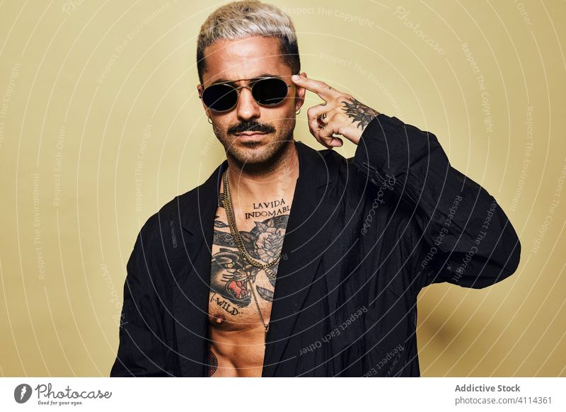 Provokativer Mann ohne Hemd in schwarzem Mantel und Sonnenbrille Macho cool trendy brutal Tattoo Stil Mode unrasiert Model Persönlichkeit muskulös Vollbart