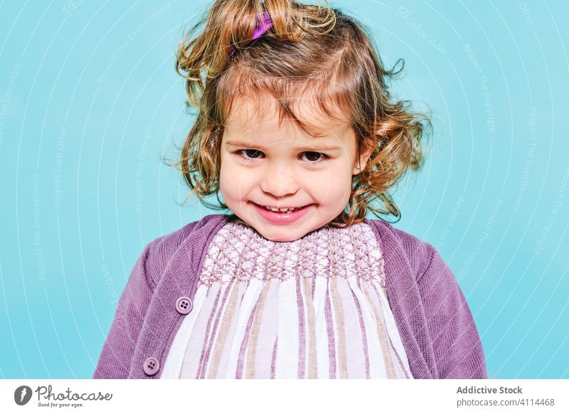 Glückliches kleines Mädchen mit süßem Lächeln im Studio Vorschule Kind Strickjacke Kleid unschuldig Frau positiv Stil Freude charmant wenig niedlich Vorschein