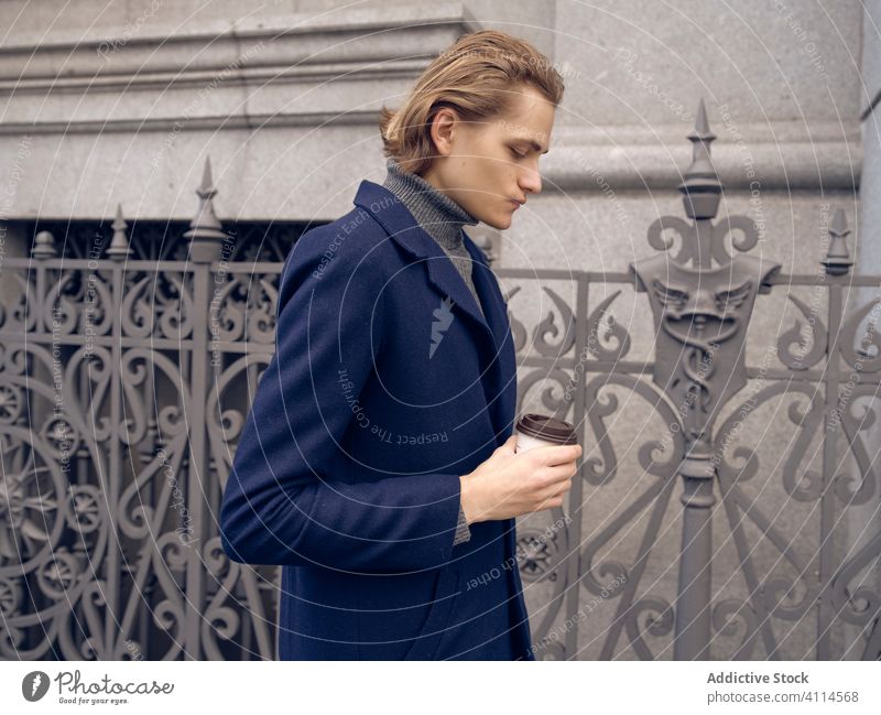 Gutaussehender stilvoller Mann mit einem Kaffee in der Stadt Stil trendy Großstadt Straße Metrosexualität urban modern trinken Mode ernst Imbissbude Zaun