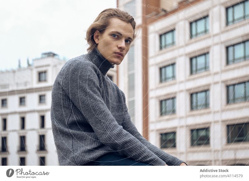 Selbstbewusster junger Mann schaut in die Kamera trendy ernst selbstbewusst Straße modern Stil Pullover gutaussehend urban Großstadt lässig Zeitgenosse Mode