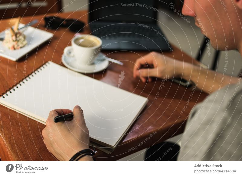 Crop Freiberufler Zeichnung in Notebook im Cafe Mann Skizze Café freiberuflich Kaffee Laptop Tisch abgelegen Projekt männlich zeichnen Notizblock Tasse Schüler