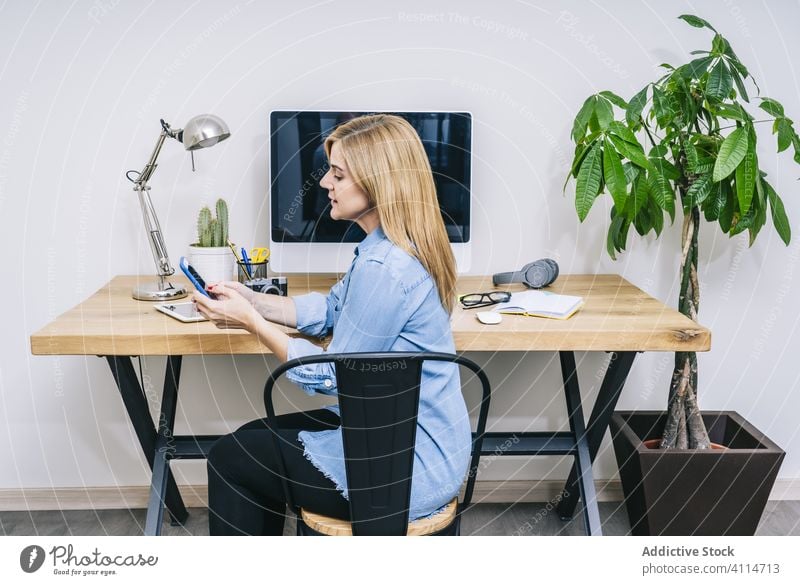 Blonde Frau arbeitet zu Hause Arbeit Schreibtisch heimwärts Smartphone Handy Mitteilung Gerät Geschäftsfrau Business im Innenbereich klug arbeiten Tisch Laptop