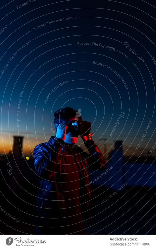 Junger Mann erforscht virtuelle Realität Nacht VR dunkel Straße Headset Schutzbrille futuristisch leuchten neonfarbig rot Licht männlich modern Gerät Apparatur