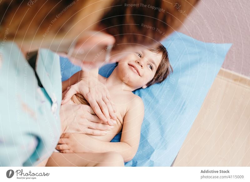 Krankenschwester untersucht kleinen Jungen in der Klinik Kind untersuchen Krankenpfleger Arzt heiter wenig Lügen Frau geduldig Krankenhaus Truhe