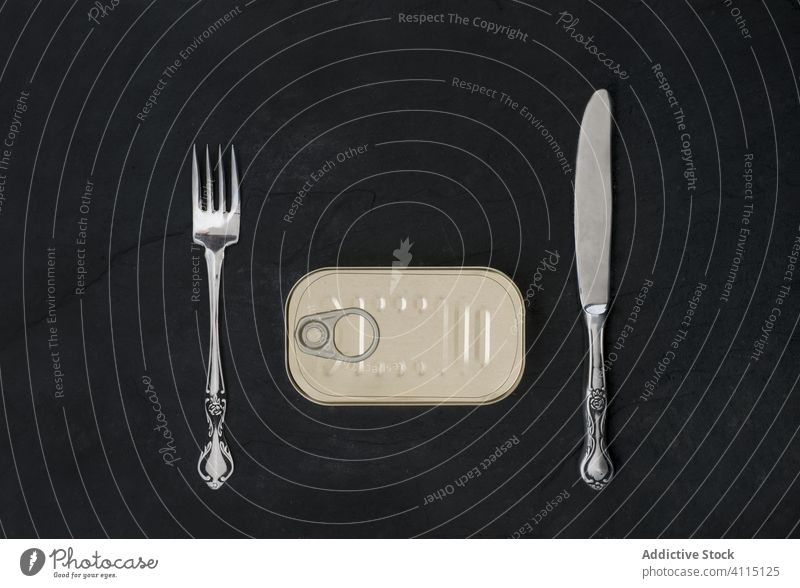 Dose mit Gabel und Messer auf schwarzem Schreibtisch Silberwaren Büchse Mahlzeit bewahren konservieren Holzplatte Sardinen Meeresfrüchte Tisch Kulisse